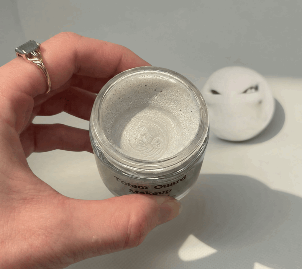 Creamy, pearlescent white Totem Guard Makeup Primer with a swirled texture inside a glass jar
