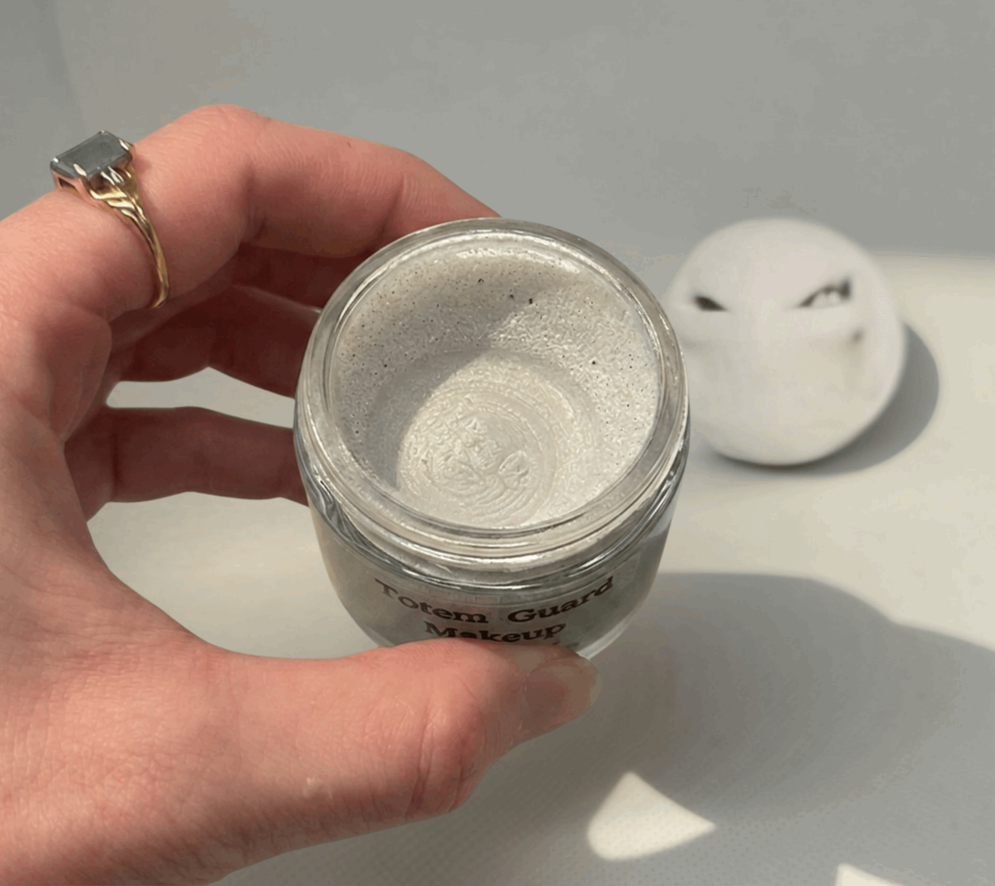 Creamy, pearlescent white Totem Guard Makeup Primer with a swirled texture inside a glass jar