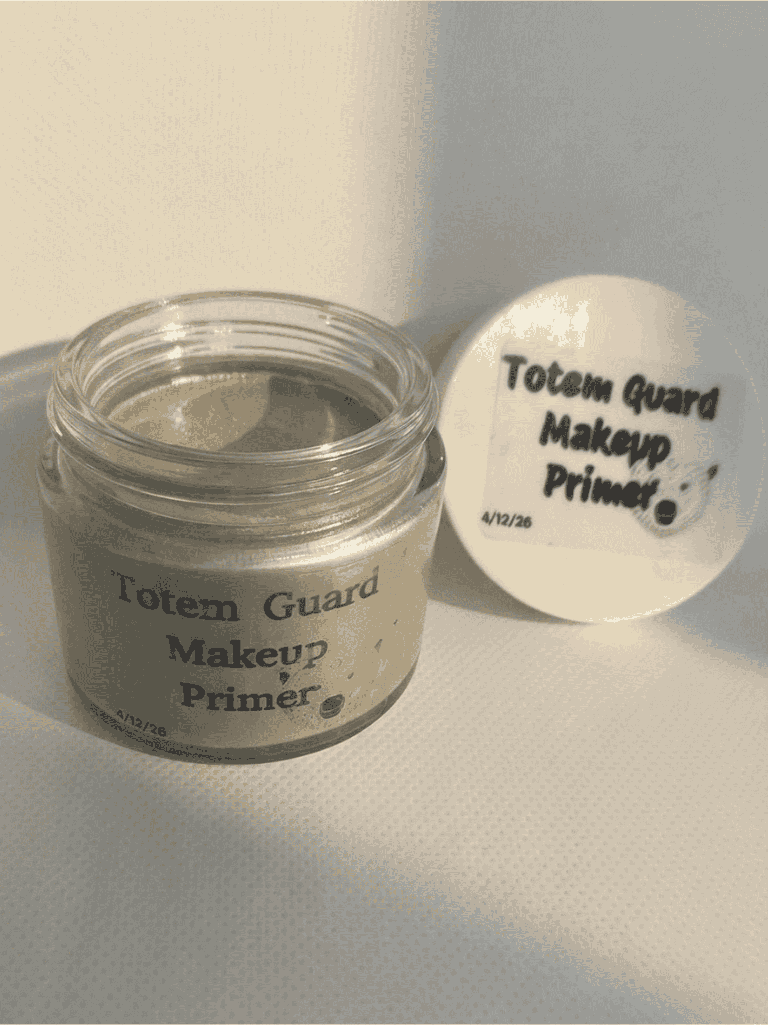Totem Guard Makeup Primer jar next to its open white lid featuring a bear illustration