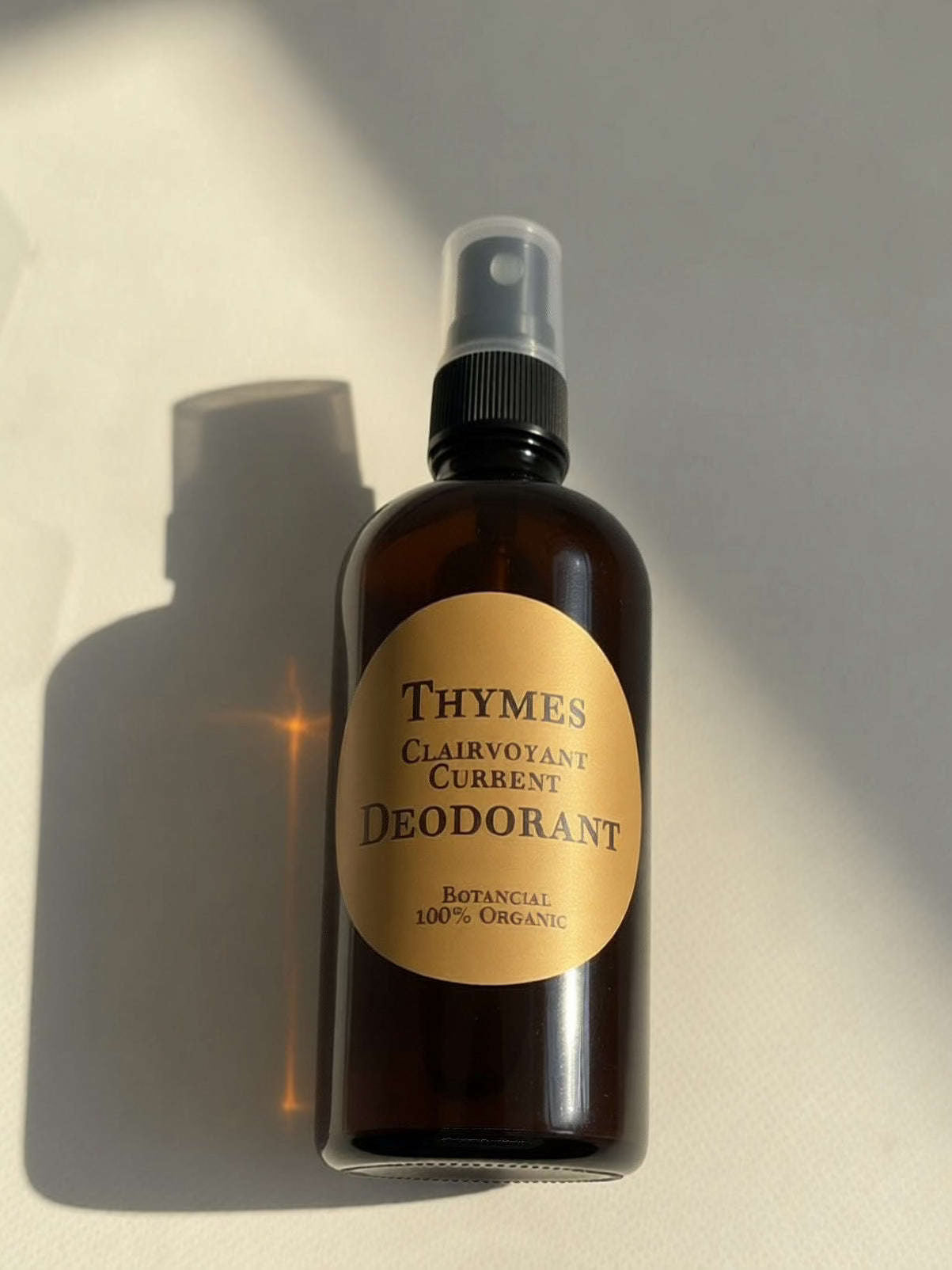 High-angle view of Thymes organic spray deodorant bottle with metallic gold label on a white background