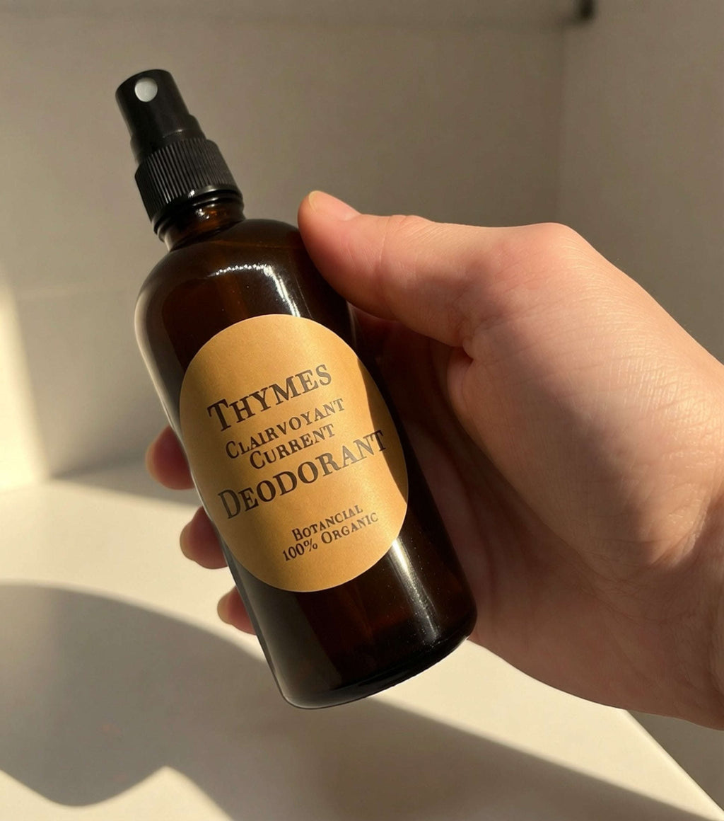 Hand holding Thymes Clairvoyant Current organic deodorant spray bottle under natural light